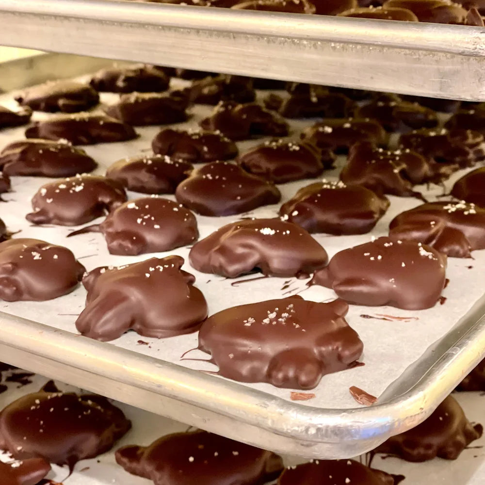 trays of dark chocolate covered pecan clusters topped with a touch of salt