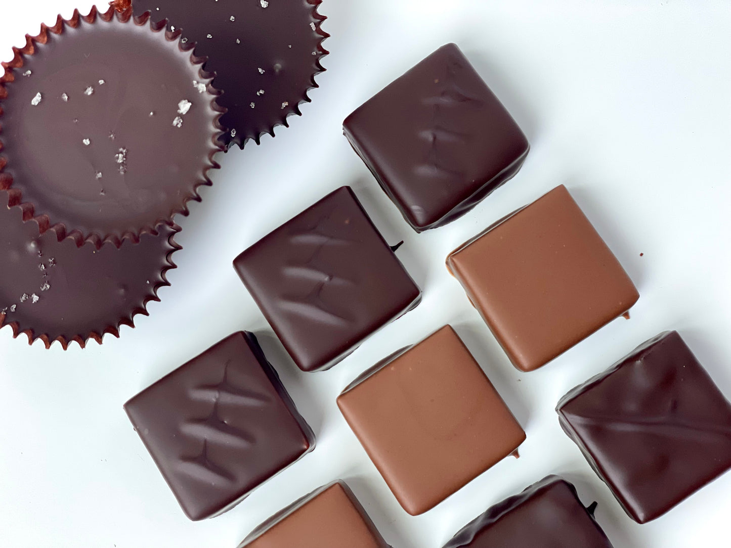 Assorted chocolate bonbon in milk and dark chocolate as well as Peanut praline cups on a white background