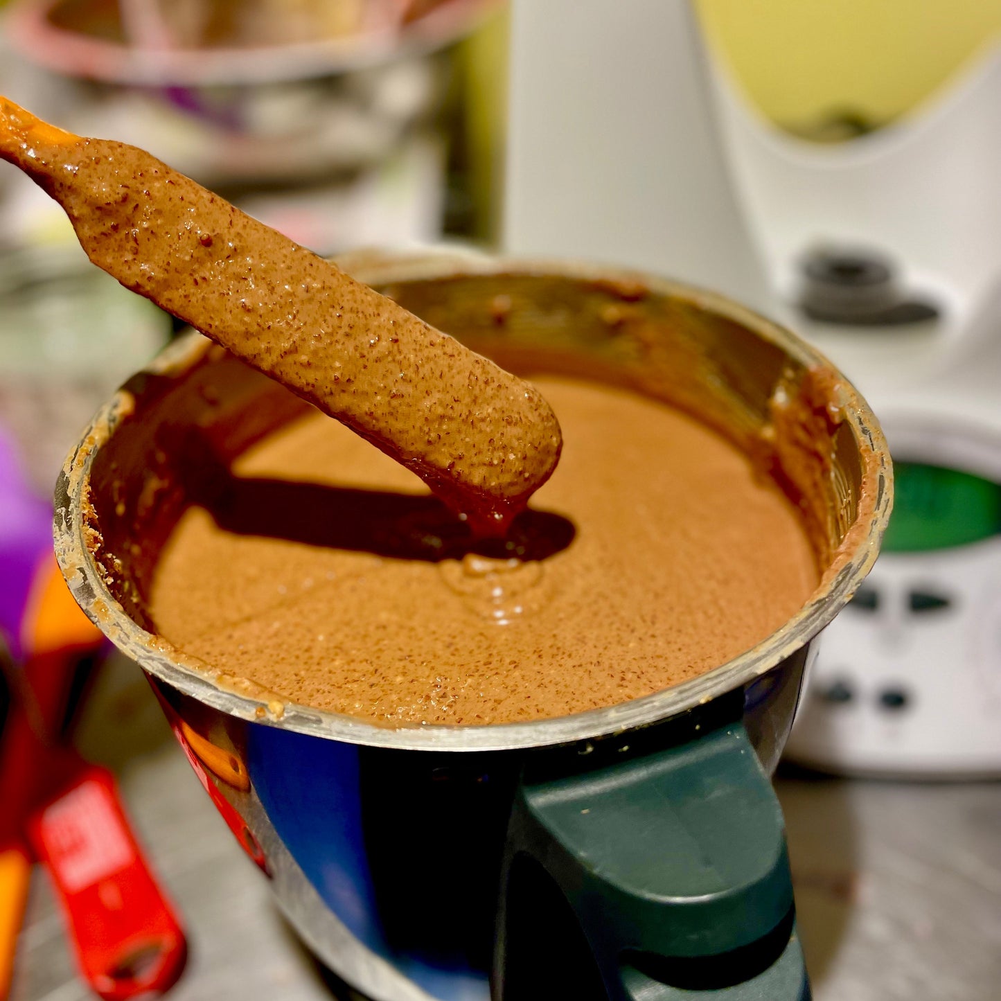 Blender with chocolate peanut praline with stirring spatula.