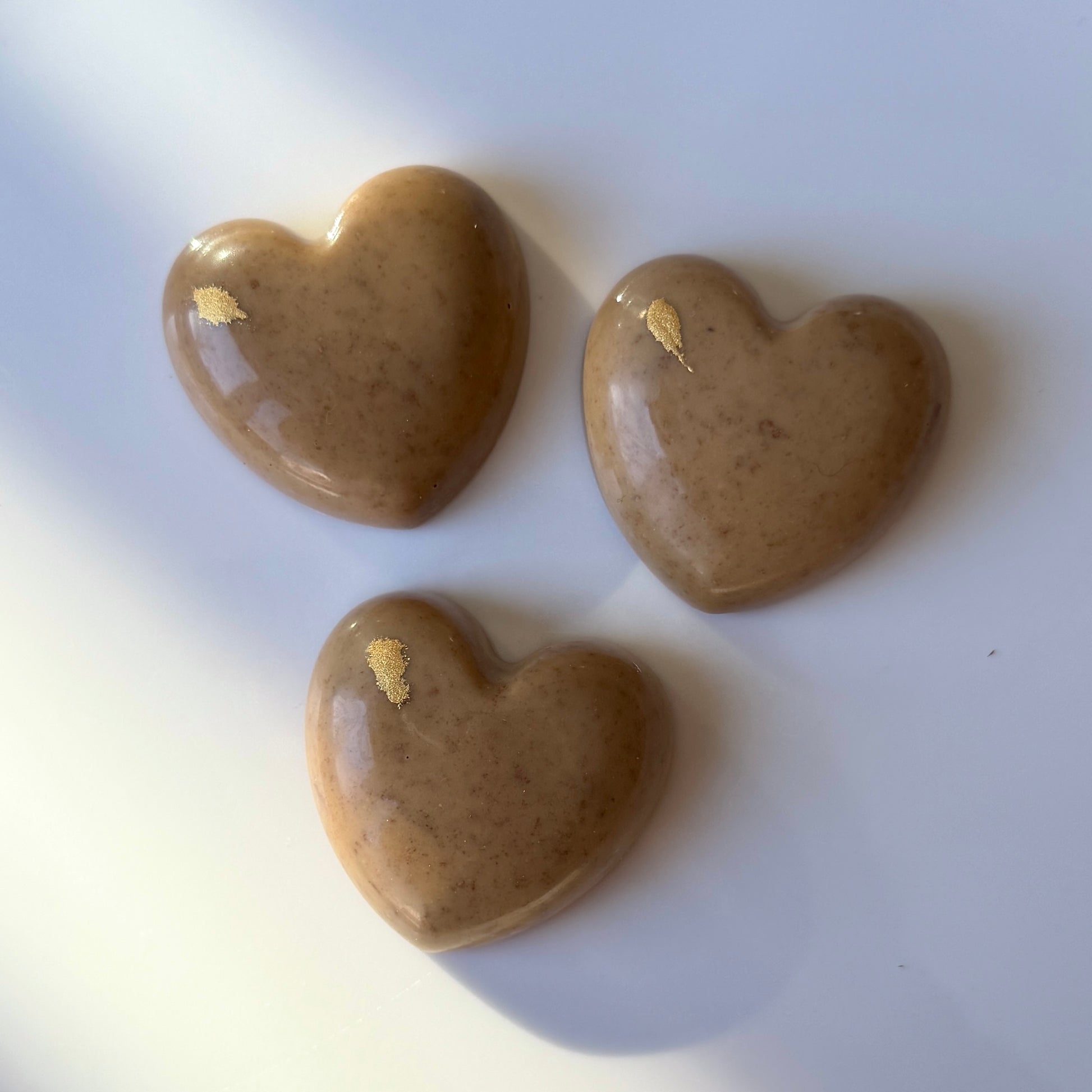 Three heart-shaped stones with gold accents on a white background