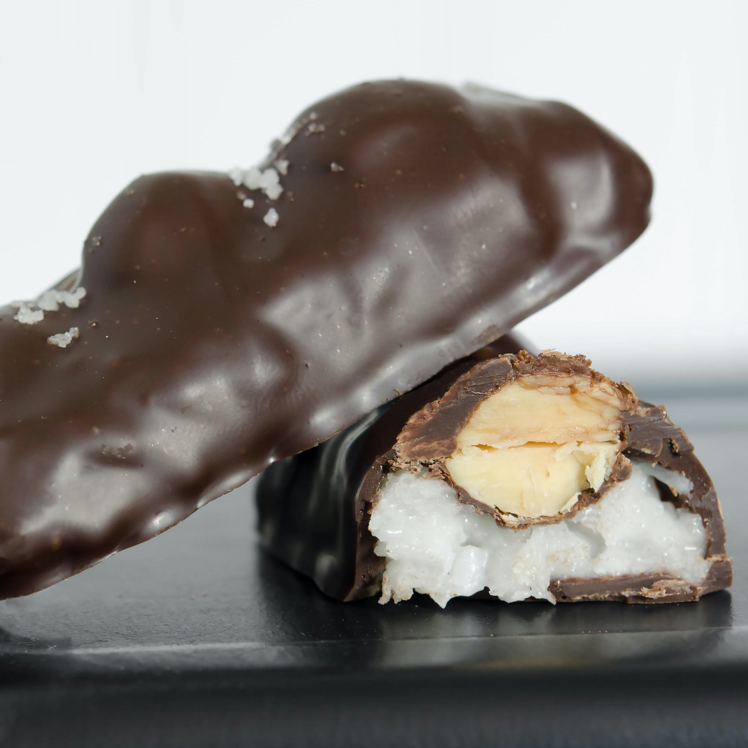 Chocolate-covered treat with a white filling on a reflective surface