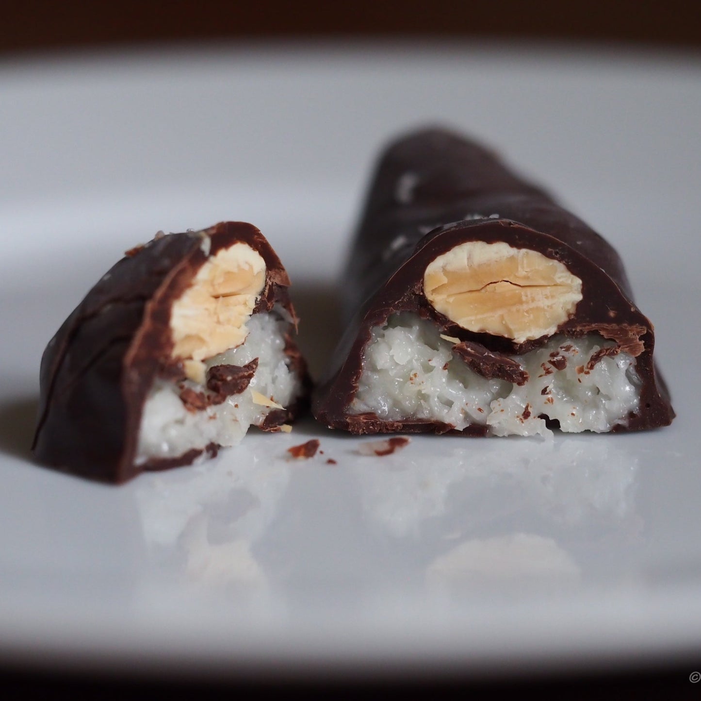 Chocolate-covered treat with a visible filling on a white plate