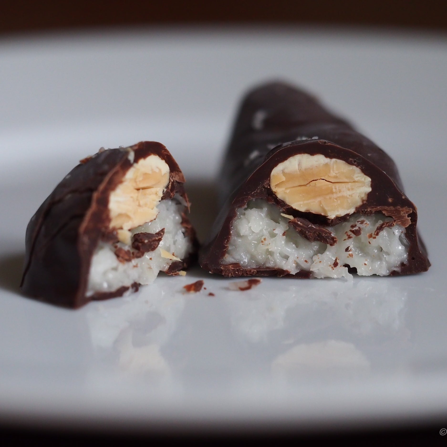 Chocolate-covered treat with a visible filling on a white plate