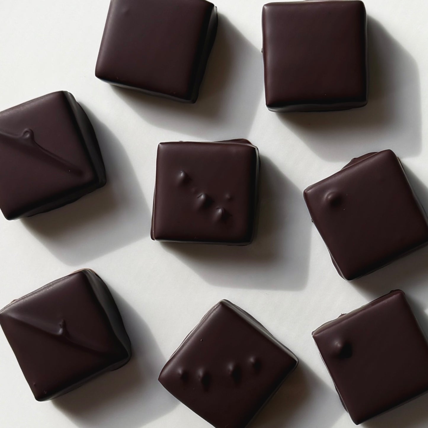 Dark chocolate candies on a light gray background