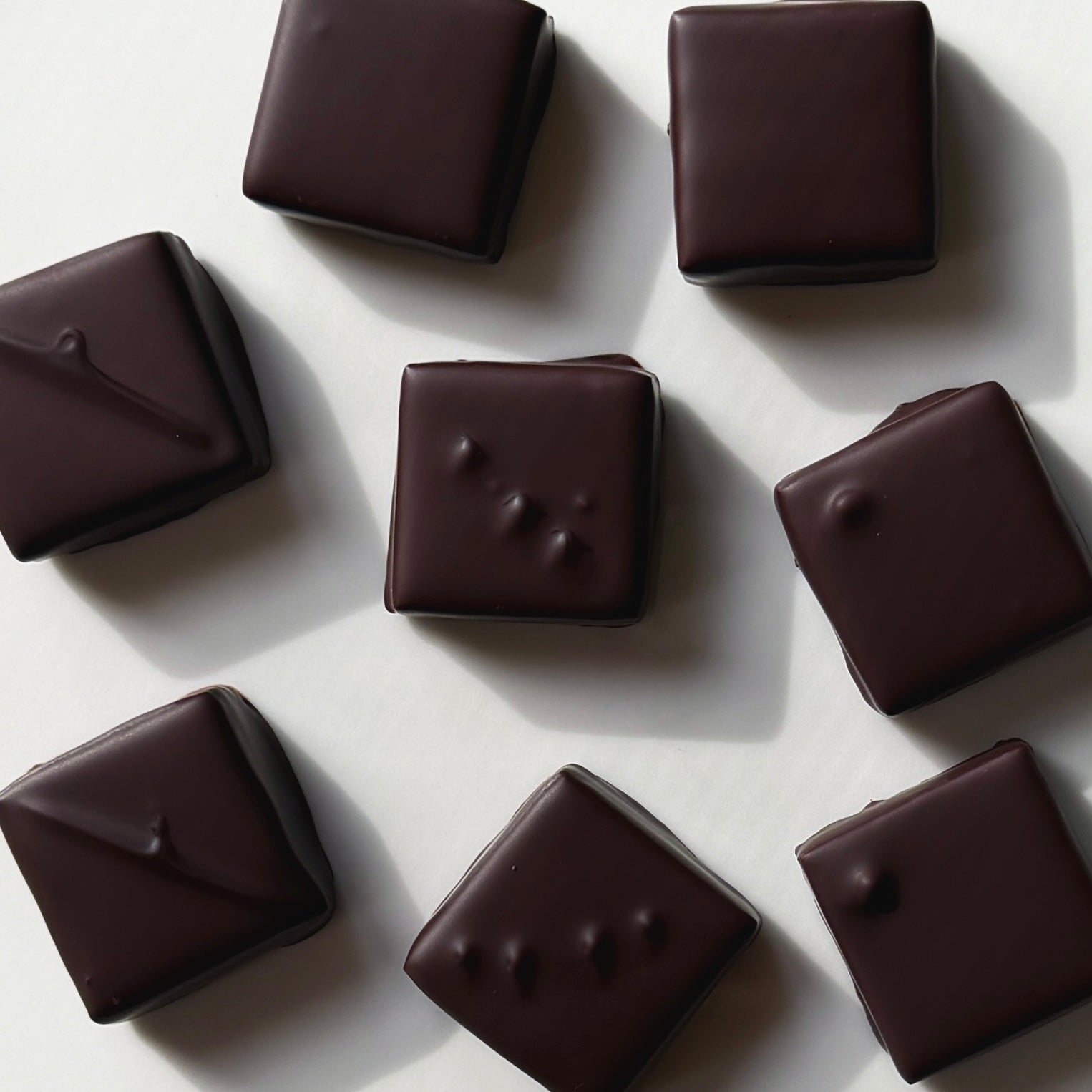 Dark chocolate candies on a light gray background