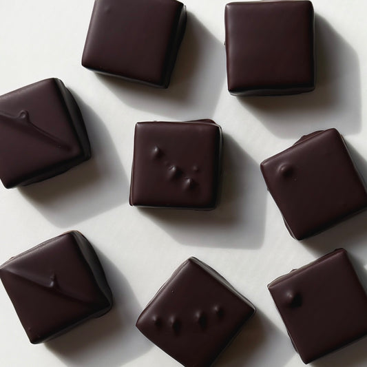 Dark chocolate candies on a light gray background