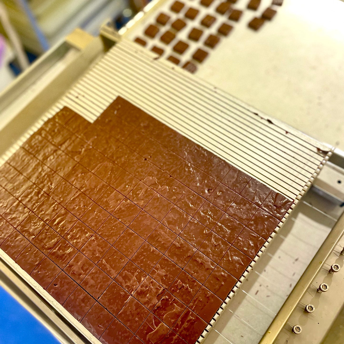 Chocolate bar being produced on a machine with a grid pattern