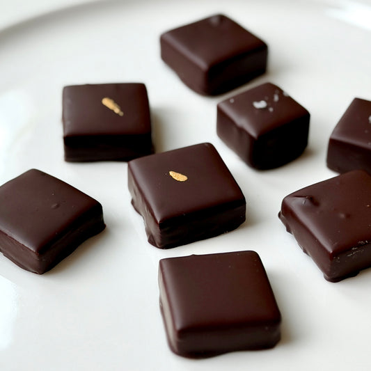 Dark chocolate squares with gold accents on a white surface