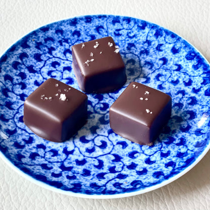 Small decorative blue plate with 3 chocolate squares, each with a light sprinkle of salt