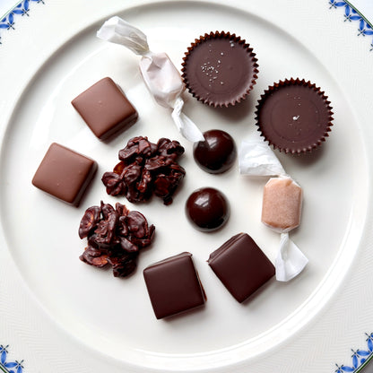 Assorted chocolate candies on a white plate with decorative edges.