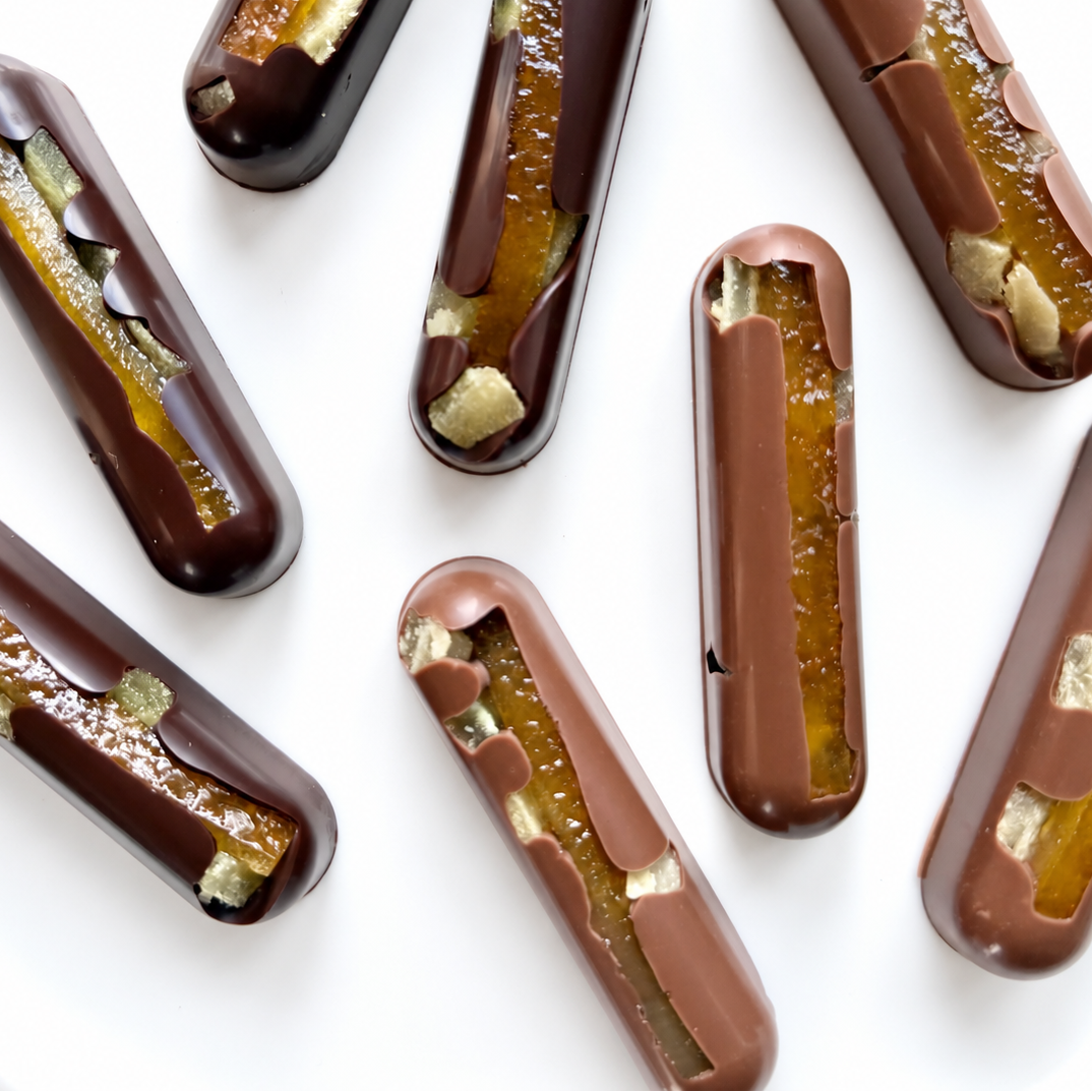 Oblong solid milk and dark chocolate bars with long orange candied zest and crystallized ginger.