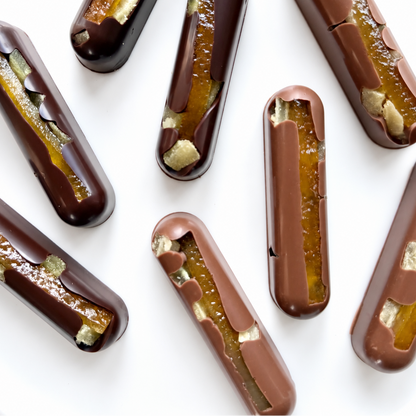 Oblong solid milk and dark chocolate bars with long orange candied zest and crystallized ginger.