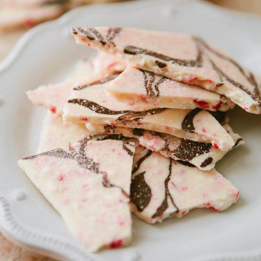 white and dark chocolate  with peppermint bits in thin bark stacked on top of each other on a white plate 
