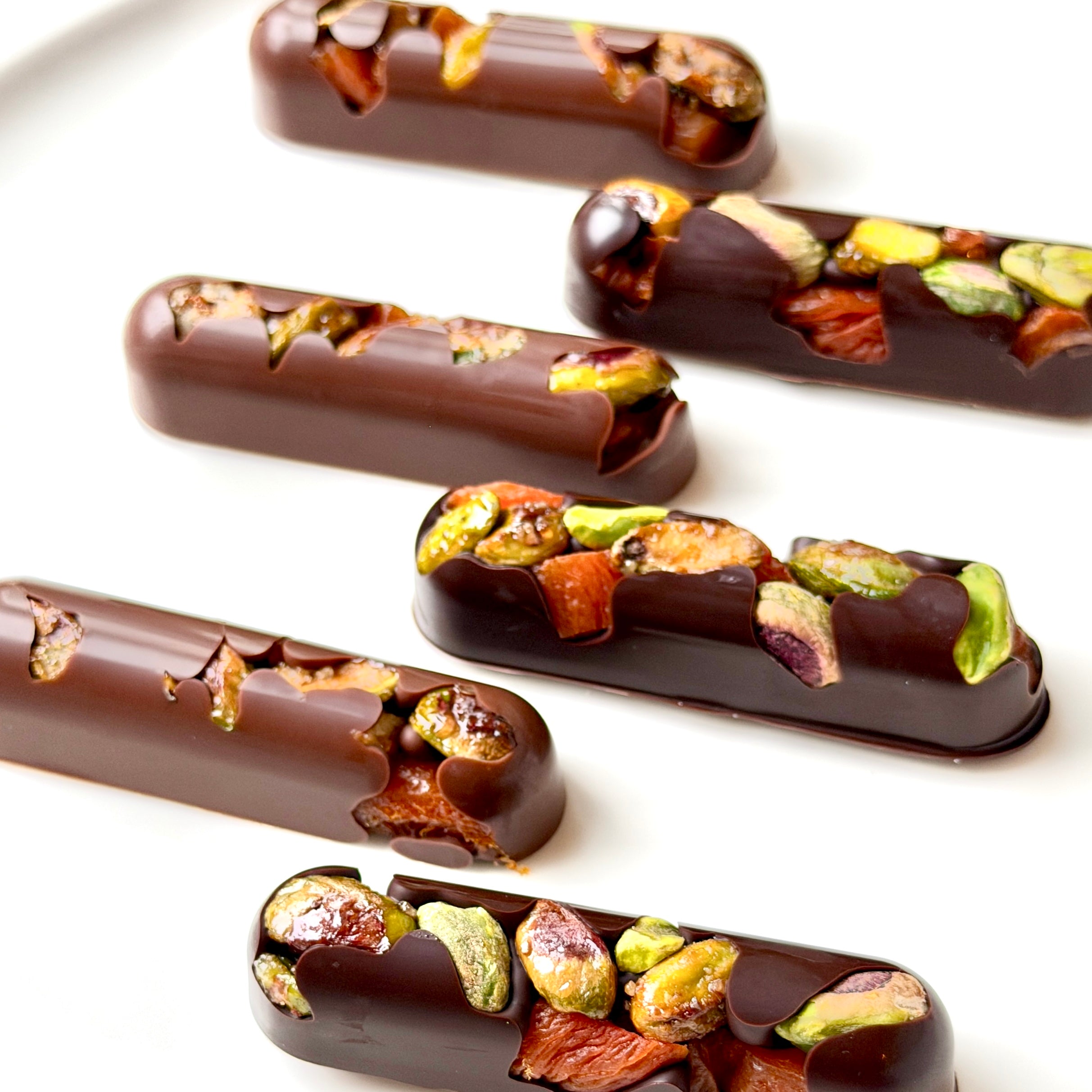Chocolate-covered treats with nuts and dried fruits on a white background