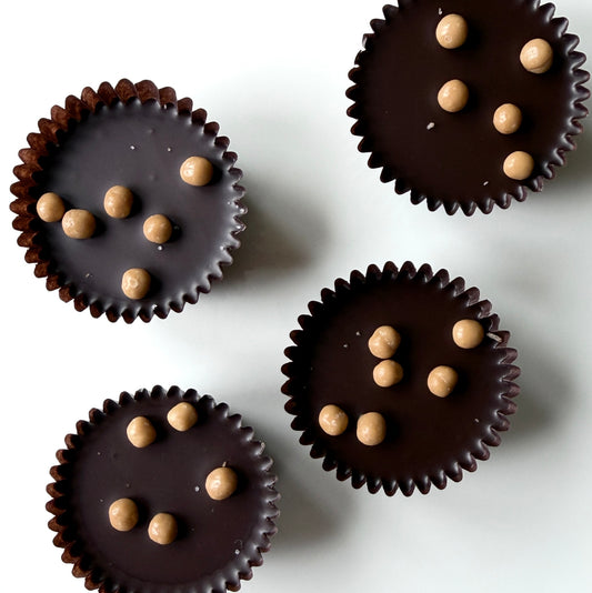 Dark chocolate cups with small round candies on a white background