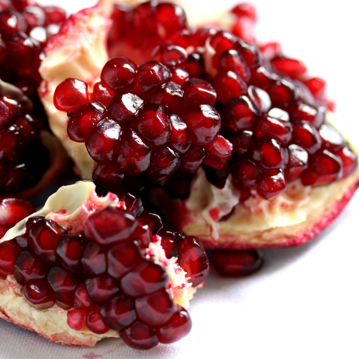 Close-up of a pomegranate with juicy red seeds on a white background