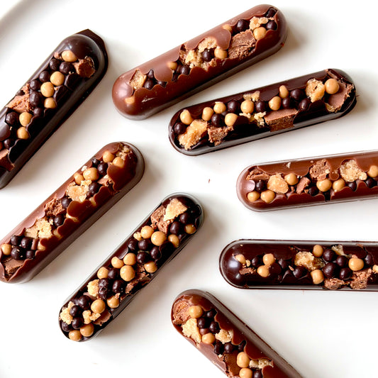 Chocolate-covered treats with nuts and chocolate chips on a white surface