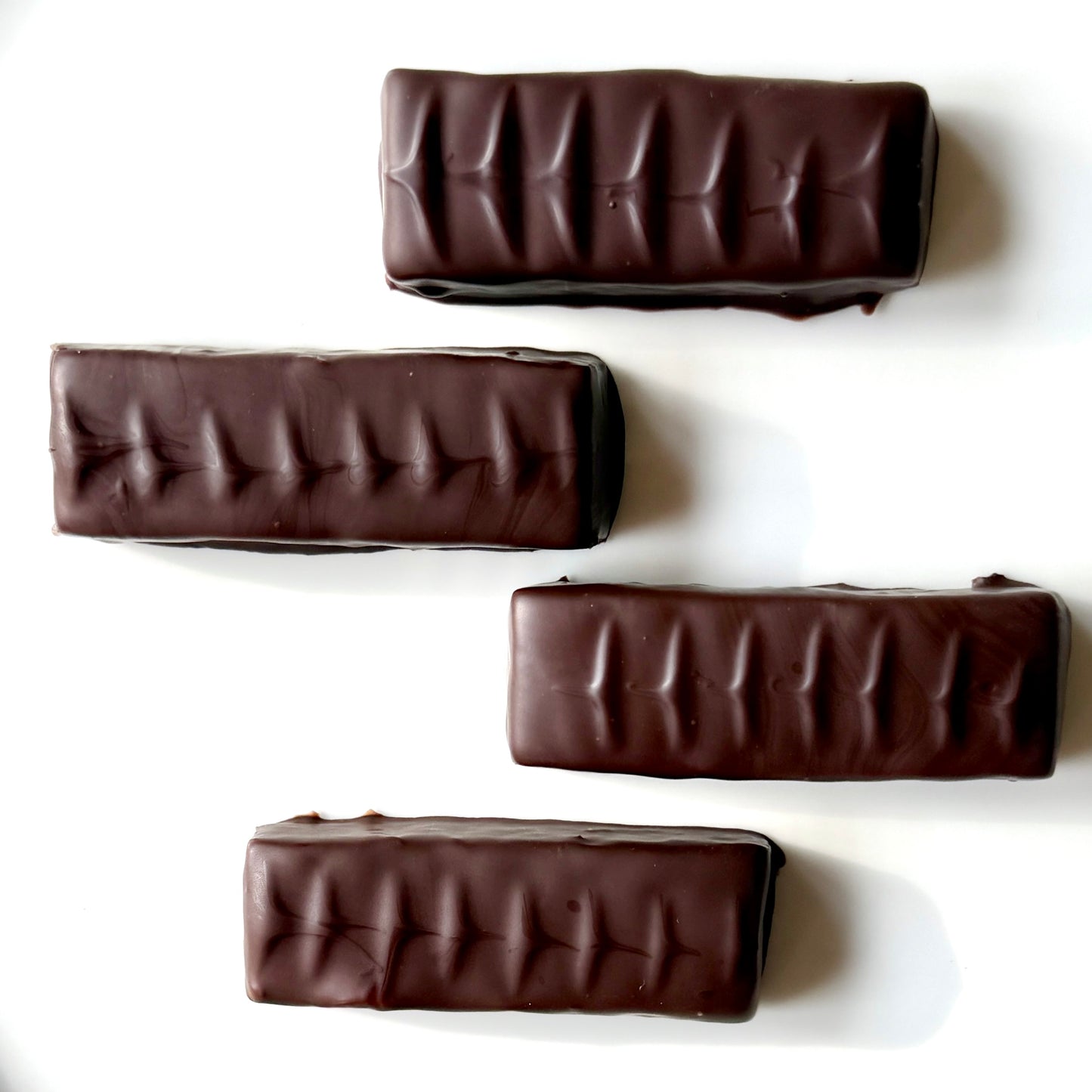 Four chocolate bars with a ribbed texture on a white background