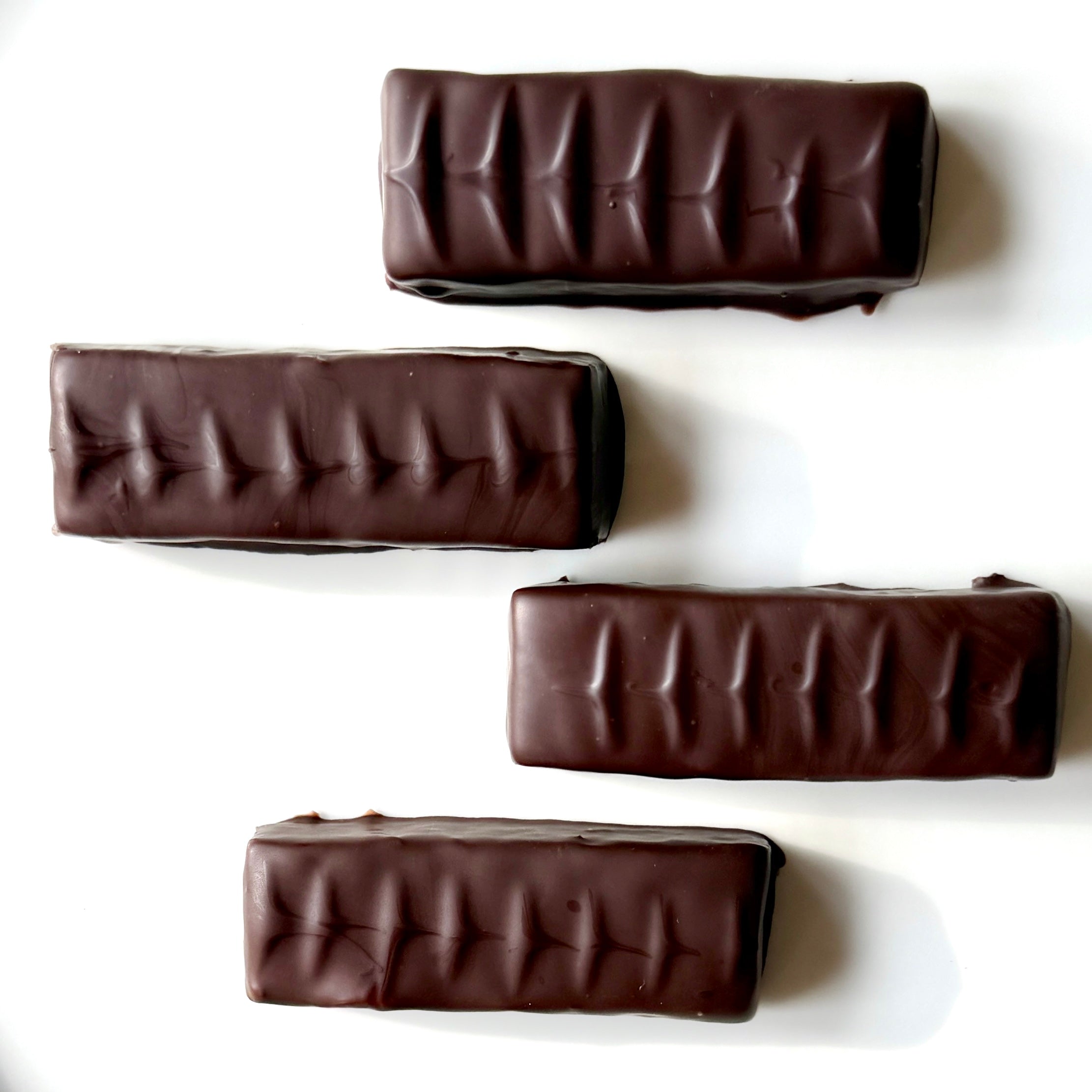 Four chocolate bars with a ribbed texture on a white background