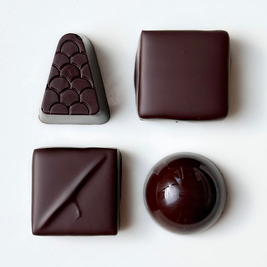Four different shapes of dark chocolate on a white background