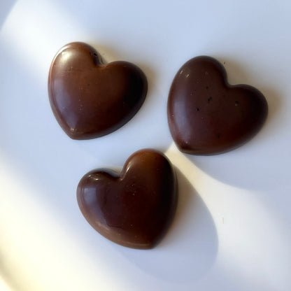 Three heart-shaped chocolate candies on a white surface
