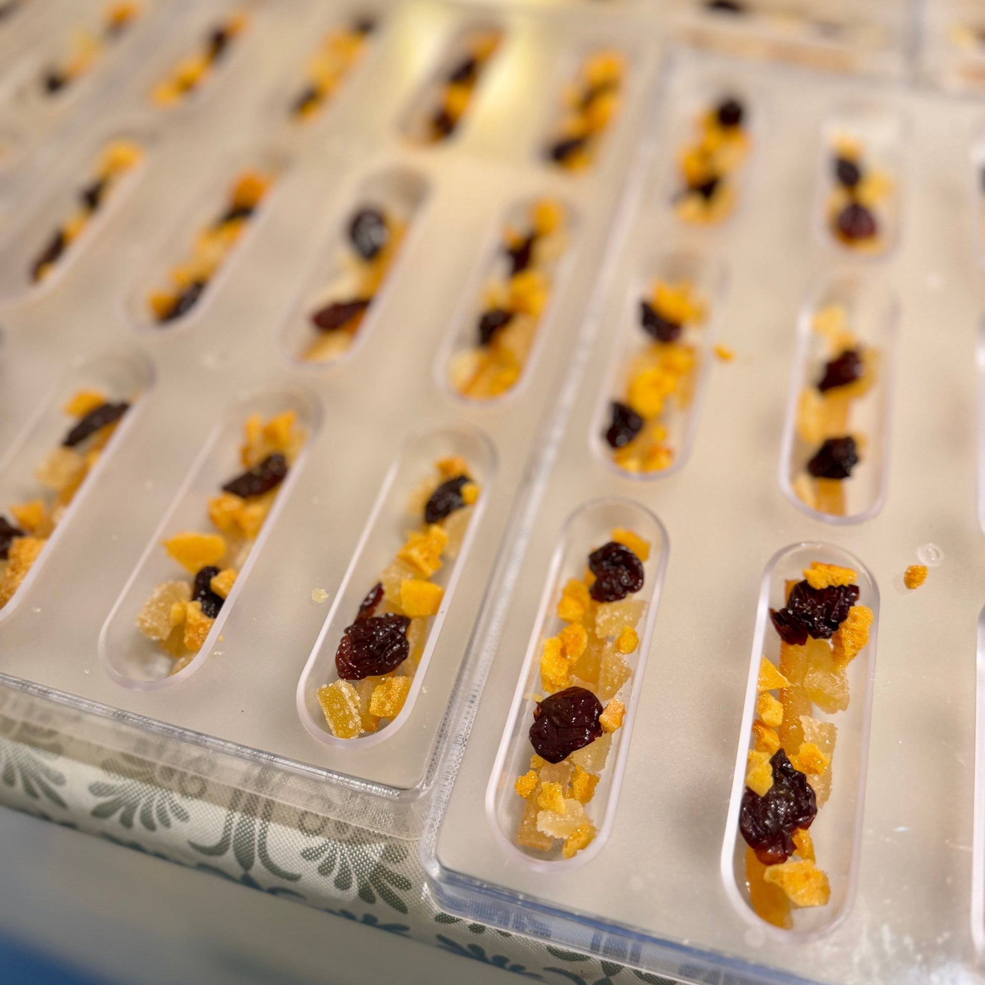 bits of candied gnger, tart cherry, honeycomb in oblong molds in a row