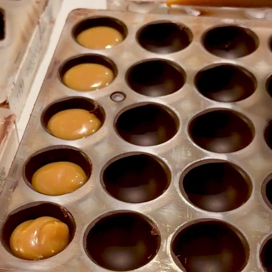 video of chocolate molds being filled with salted caramel ganache
