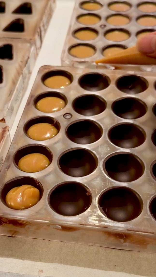 video of chocolate molds being filled with salted caramel ganache