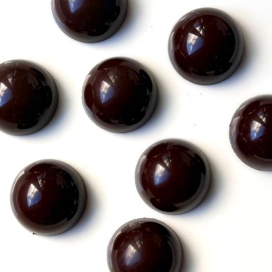 eight dark brown half dome chocolates on a white background